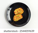 Korean style rolled omelette (Gyeran-mari). Omelette with chopped red paprika, sliced green onion and chopped carrot. On a black plate isolated on white background. Top view