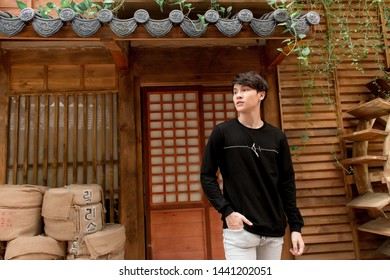 Korean Town, Ho Chi Minh City, Vietnam, June 27 2019: Outdoor Portrait, Man Wearing Sweatshirts, Jeans Or Khaki Pants, Walking On The Road In Front Of Korean Shops