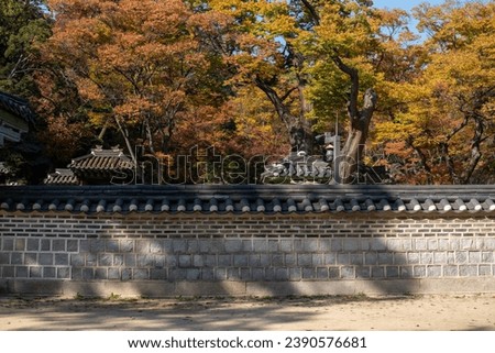 Korean traditional stone wall in Changdeokgung palace with beautiful autumn foliage.
