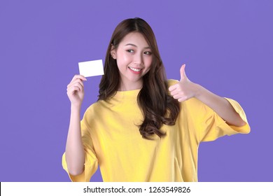 Korean woman use blank credit card to pay online shopping, yellow t-shirt clothing, purple background