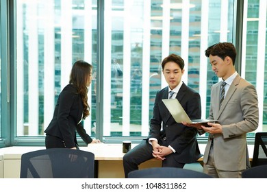 Korean workers looking at laptop screen  - Shutterstock ID 1048311862