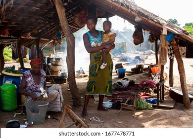 Korhogo, Ivory Coast - 10 26 2017: African Women Cooking And Taking Care Of Their Children In An Open Hut. It Is Close To A Weaving Production Site In A Small Village In The North Of The Country.