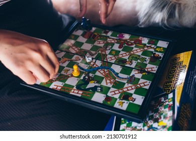 KORONADAL, PH – DEC 25, 2021: Girls's Hand Playing The Popular Snakes And Ladders Board Game AKA Moksha Patam, Chutes And Ladders, Or Bible Ups And Downs Of 10x10 Board. 