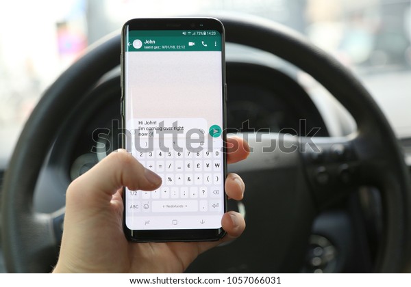 KORTRIJK, BELGIUM -JANUARY 30ST 2018: Person\
texting and driving on a Samsung Galaxy S8 phone. The left hand\
typed a message on the WhatsApp app. Concept of dangerous behavior.\
Illustrative\
editorial.