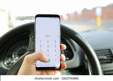 KORTRIJK, BELGIUM- MARCH 5TH 2018: Hand Of A Car Driver Holding His Mobile Phone, Dailing The Emergency Number 911 On The Numeric Dail Pad. A Concept Of A Road Accidentand Help. Illustrative Editorial