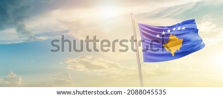 Kosovo national flag waving in beautiful sky.