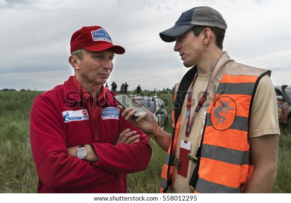 KOSTANAY, KAZAKHSTAN-JULY 12, 2016: The head of the\
rally Vladimir Chagin gives an interview to an American reporter\
before the start of stage 4 during the Silk Way rally\
Moscow-Beijing Dakar series\
