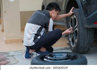 Kota Bharu, Malaysia - August 1st, 2020 : A Teenager Is Changing A Wheel On A Car. Car On Maintenance, Repair Service.