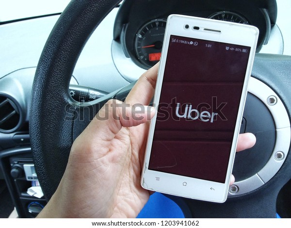 Kota Kinabalu, Malaysia\
- Oct 13, 2018 : A woman hand holding Uber app showing on mobile\
smartphone in the car,Uber is smartphone app-based transportation\
network.