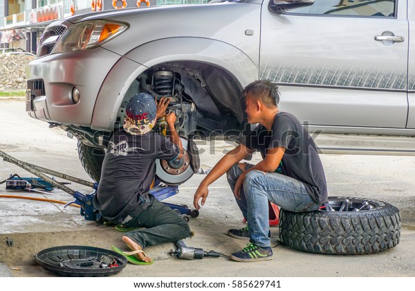 Kota\
Kinabalu,Sabah-Aug 11,2016:The car mechanics checking shock\
absorber in car suspension at garage at Kota Kinabalu,Sabah.Shock\
absorbers can also leak as they are filled with\
oil.