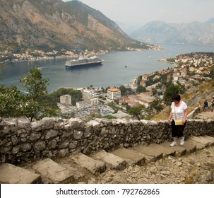 Kotor, Montenegro - August 2013: Person walking up steps to the castle with a cruise ship in the background