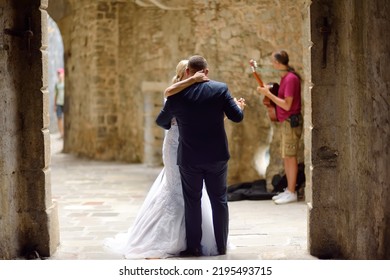 Kotor, Montenegro - August 23, 2022: Romantic Wedding Scene On The Street Of Kotor Old Town. Street Musician Playing Guitar And Couple Of Newlyweds Dancing. Marriage In Historical Places.