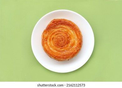 Kouign Amann Croissant Served On Plate Isolated On Green Background