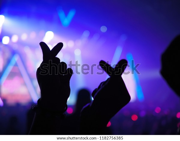K Popの音楽テーマまたはライブコンサートの背景にシルエット手を使って ぼかした背景にアーティストがネオン光を当て ミニハート形の手のジェスチャーを作ります の写真素材 今すぐ編集