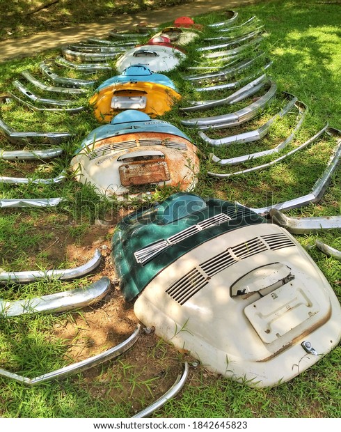 Krabi Town, Krabi\
Province / Thailand - September 26, 2019: Modern art installation\
made of Volkswagen Bug parts including back hatches and fenders or\
bumpers  on green grass