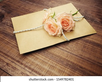 Kraft Envelope, Old Paper Tied With Rope, Old Twine, On Top Of Gently Pink Roses, The Concept Of A Gift, A Surprise. Congratulations On Valentine's Day, Happy Birthday. I Love You.