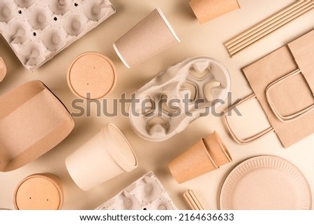 Kraft paper eco food packaging over light brown background. Street food sustainable paper packaging, recyclable paperware, zero waste packaging concept. Flat lay, mockup image. Paper utensils