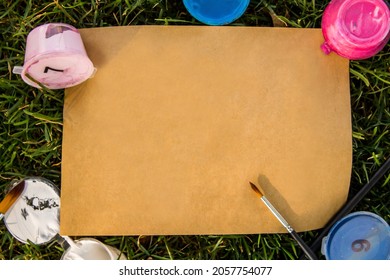 Kraft Paper Rectangular Blank Sheet, Mock Up With Acrylic Color Paint Cans Under Numbers And Paint Brushes On Green Grass. Top View Background. Blank Template