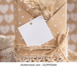 Kraft Paper Wrapped Present With Square Gift Tag And Pampas Grass Close Up. Summer Scene With Blank Label. Rustic, Cottage Chic Or Bohemian Mockup, Copy Space