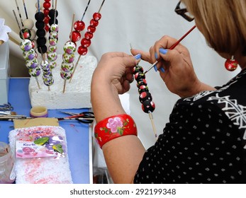 KRAKOW, POLAND - August 23, 2014: one of the exhibitors of International Folk Art Fair "Cepelia" in Krakow, paints a bead.