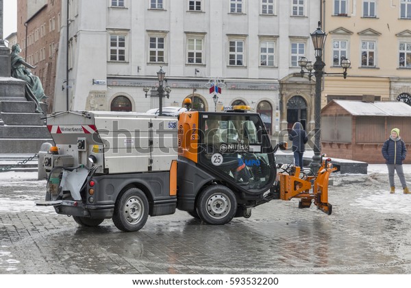 KRAKOW, POLAND - JANUARY 12, 2017: Unrecognized
driver works on small snow blower truck on main city Market square
( Rynek Glowny ). Krakow is the second largest and one of the
oldest cities in Poland