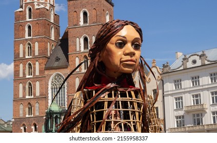 KRAKOW, POLAND - MAY 13, 2022: Little Amal, giant puppet representing Syrian refugee child. Arrives in Kraków to visit Ukrainian war refugees. Saint Mary's Basilica (Mariacki Church) in background.