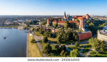 Krakow, Poland. Wide aerial panorama at sunset with Royal Wawel castle and cathedral. Vistula river banks, tourist boats, parks, promenades and walking people