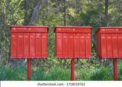 Krakow/Poland - 27 April 2020: Bright Red Outdoor Cluster Mail Boxes With Individual Slots In Rural Poland. The Text In Polish On The Mailbox Translates To: 'The Post Office Of Poland'                