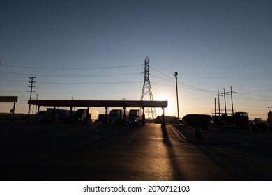 Krammer Junction, California, September 18, 2021: A Gas Station In The Desert At Sunset As The Structure, Tanks, And Trucks Refueling Are Silhouetted By The Light Symbolizing Solar Energy