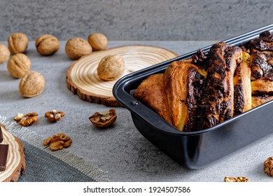 Krantz cake with chocolate and nuts filling in black baking tin mold. Yeast-risen dough twisted cake. 