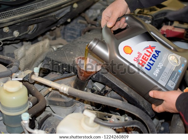 Krasnodar, Russia - April 22, 2017: Oil change\
in the engine of the car. Filling the oil through the funnel. Car\
maintenance station.