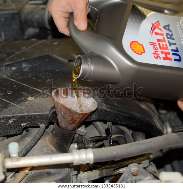 Krasnodar, Russia - April 22, 2017: Oil change\
in the engine of the car. Filling the oil through the funnel. Car\
maintenance station.
