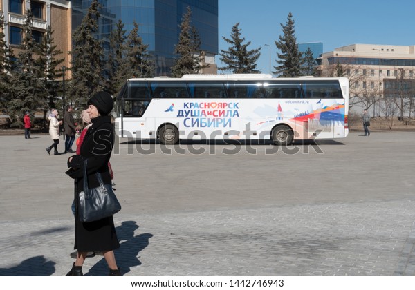 Krasnoyarsk, Krasnoyarsk Region / RF - April 5,\
2019: An elderly woman is waiting for a two-story tour bus with the\
inscription \