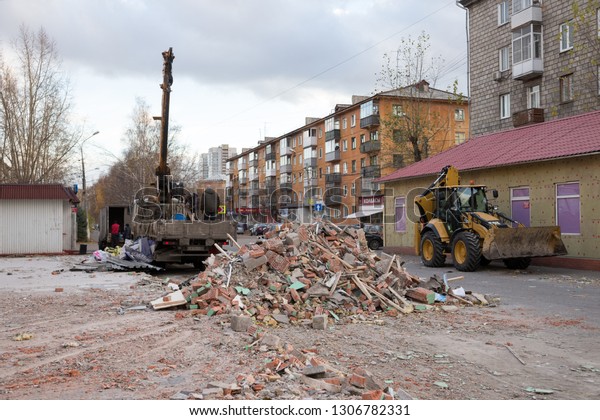 Krasnoyarsk, Krasnoyarsk Region / RF - October\
29, 2018: Pile of demolition waste of old pavilions lies on the\
city street near the bulldozer and truck during the work process in\
the autumn.