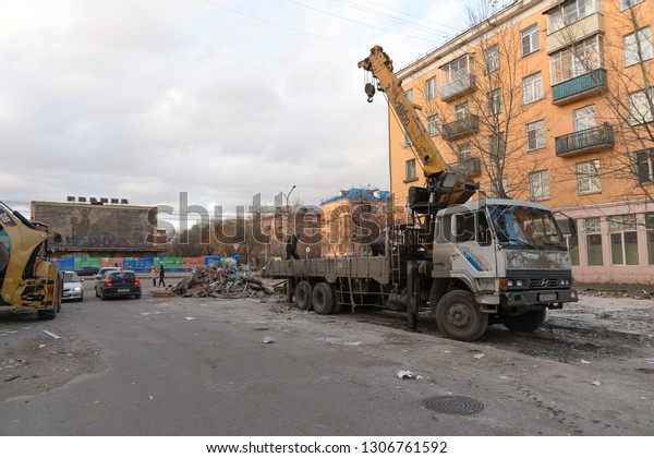 Krasnoyarsk, Krasnoyarsk Region /RF - October\
29,2018: Public service workers put construction waste from the\
demolition of old pavilions in a truck in an alley near a\
residential\
building.