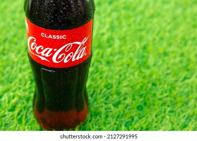 Krasnoyarsk, Russia - 07.14.2020: Glass Bottle Of Coca Cola Covered With Drops Stands On Green Grass Of Lawn. Refreshing Drink. Quenching Thirst. Harm To Health. Unhealthy Food, Drink. Place For Text.