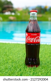 Krasnoyarsk, Russia - 07.14.2020: Glass Bottle Of Coca Cola Stands On Green Grass Of Lawn. Refreshing Drink. Quenching Thirst. Harm To Health. Unhealthy Food And Drink