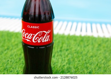 Krasnoyarsk, Russia - 07.14.2020: Glass Bottle Of Coca Cola Stands On Green Grass Of Lawn. Refreshing Drink. Quenching Thirst. Harm To Health. Unhealthy Food And Drink. Place For Text.