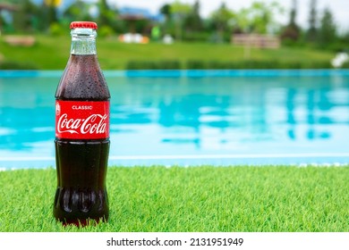 Krasnoyarsk, Russia - 07.14.2020: Glass Bottle Of Coca Cola Covered With Drops Stands On Green Grass Of Lawn. Refreshing Drink. Quenching Thirst. Harm To Health. Unhealthy Food, Drink. Place For Text.