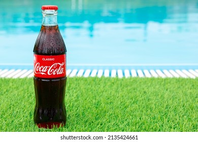 Krasnoyarsk, Russia - 07.14.2020: Glass Bottle Of Coca Cola Covered With Drops Stands On Green Grass Of Lawn. Refreshing Drink. Quenching Thirst. Harm To Health. Unhealthy Food, Drink. Place For Text