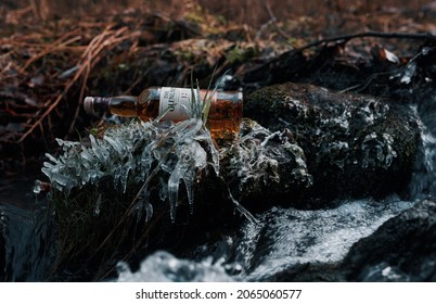 Krasnoyarsk, Russia - 10.24.2017
A bottle of Glenlivet single malt Scotch whiskey lies by a stream with icy grass.
