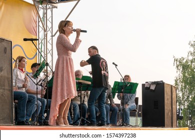 Krasnoyarsk, Russia, August 25, 2019: Female Soloist Singer In A Pink Dress Sings Outdoors, On The Street, To The Accompaniment Of The Krasnoyarsk Brass Band.