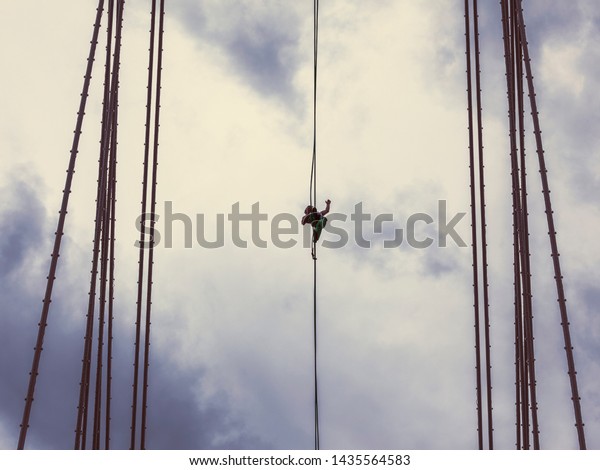 Krasnoyarsk,\
Russia - June 8, 2019: Rope-walker Maxim Kagin, on the day of the\
city, walked along a tightrope that was pulled between the supports\
of the cable-stayed Vinogradovsky\
bridge
