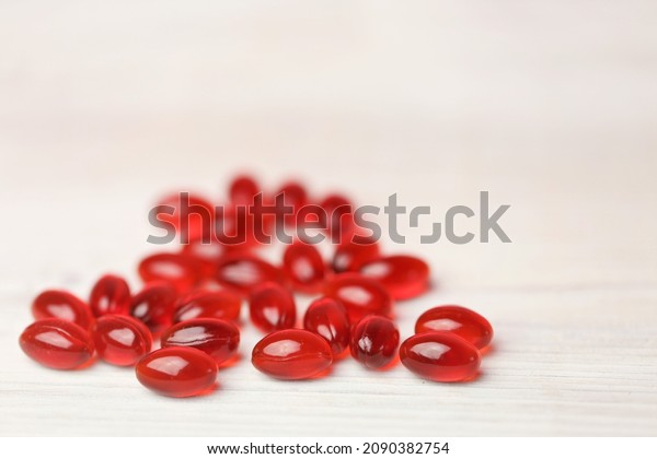 Krill oil red gelatin capsules\
set on a white wooden background .Natural supplements and\
vitamin