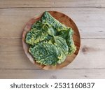 kripik bayam or Spinach crispy in plate on the wooden table. Vegetarian cuisine, Indonesian food 