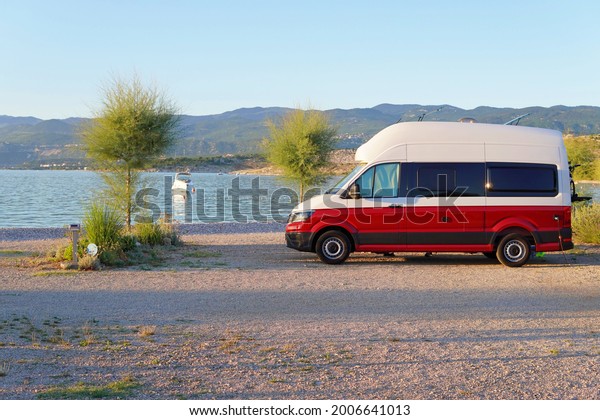 Krk, Croatia -\
July 1, 2021: Red camper van on the beach, motorhome in camping\
with sea view, van life\
concept.