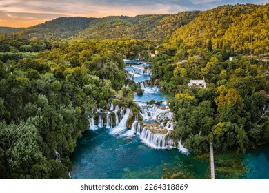 Krka, Croatia - Aerial panoramic view of the beautiful Krka Waterfalls in Krka National Park on a sunny summer morning with green foliage, turquoise water and gold and blue sky at sunrise
