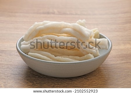 Krupuk or Kerupuk, Indonesia traditional crackers, served on small plate on woodenbackground. Selected focus image.