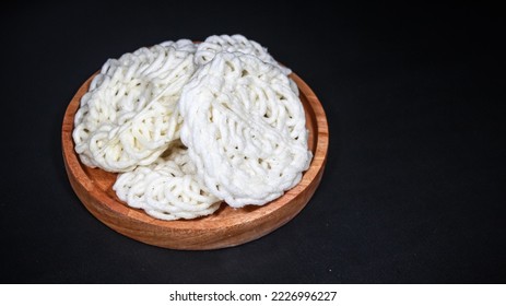 Krupuk Uyel or Kerupuk Uyel is one of type Indonesia traditional crackers. Served in wooden plate. Isolated on black background. Close up. - Shutterstock ID 2226996227
