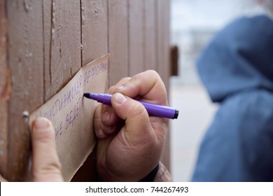 Kryvyi Rih, Ukraine - October 29, 2017:  Hand With Felt Pen Writing Theses On Th Brown Paper With Blurred Man In Hood Plaing Martin Luther During Event Dedicated To Reformation 500th Anniversary